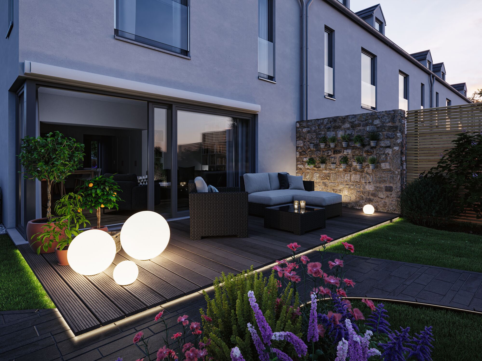 Moderne Terrasse mit runden weißen LED-Leuchtkugeln auf Holzdeck und Gartenmöbeln aus Polyrattan.