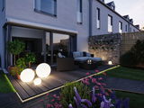 Modern terrace with round white LED light spheres on wooden deck and polyrattan garden furniture.
