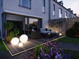 Modern terrace with round white LED light spheres on wooden deck and polyrattan garden furniture.