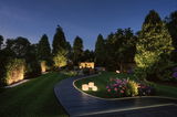 Verlichte tuinpad met LED-inbouwspots en verlichte kubussen in groene omgeving 's nachts