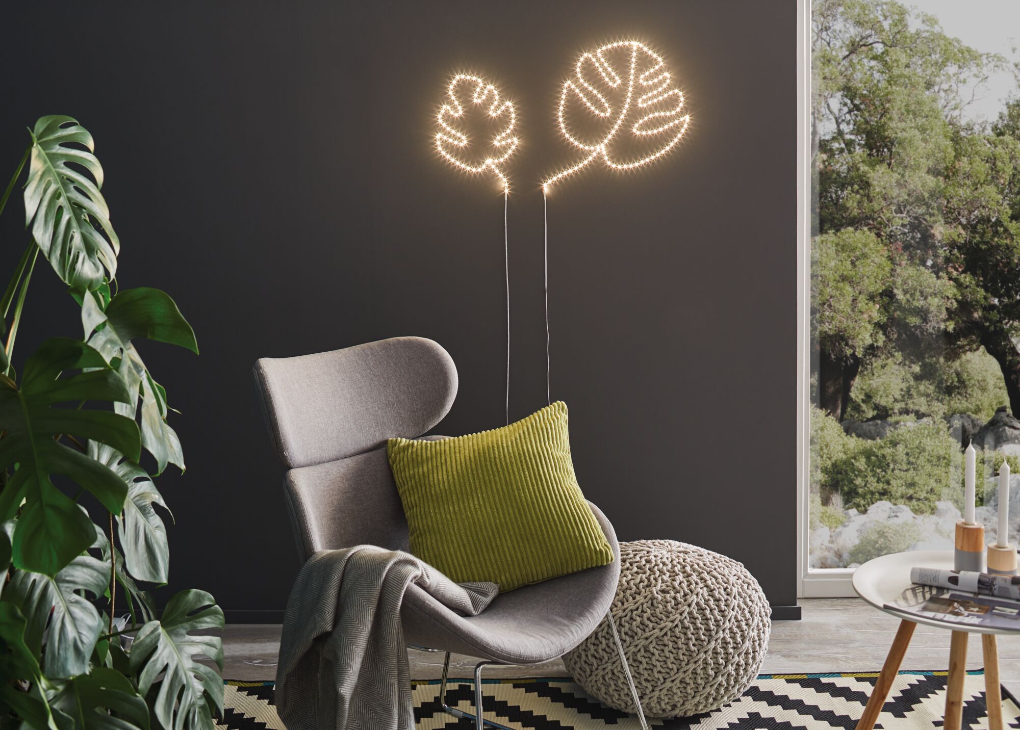 Moderne LED-Wandbeleuchtung in Blattform mit warmweißem Licht an dunkler Wand im Wohnzimmer.