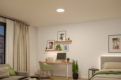 Round white LED ceiling light in modern bedroom with desk and green decor plants