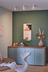 Trois spots de plafond blancs en métal sur plafond blanc dans un salon moderne avec mur vert.