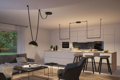 Moderne offene Küche mit weißer Holzinsel, schwarzen Barhockern und minimalistischer schwarzer Pendelleuchte