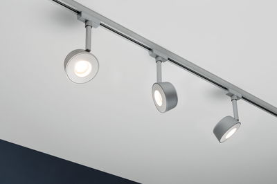 Drei silberne LED-Schienenstrahler aus Metall an weißer Decke für moderne Innenbeleuchtung.