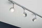 Trois spots LED en métal argenté fixés au plafond blanc pour un éclairage intérieur moderne.