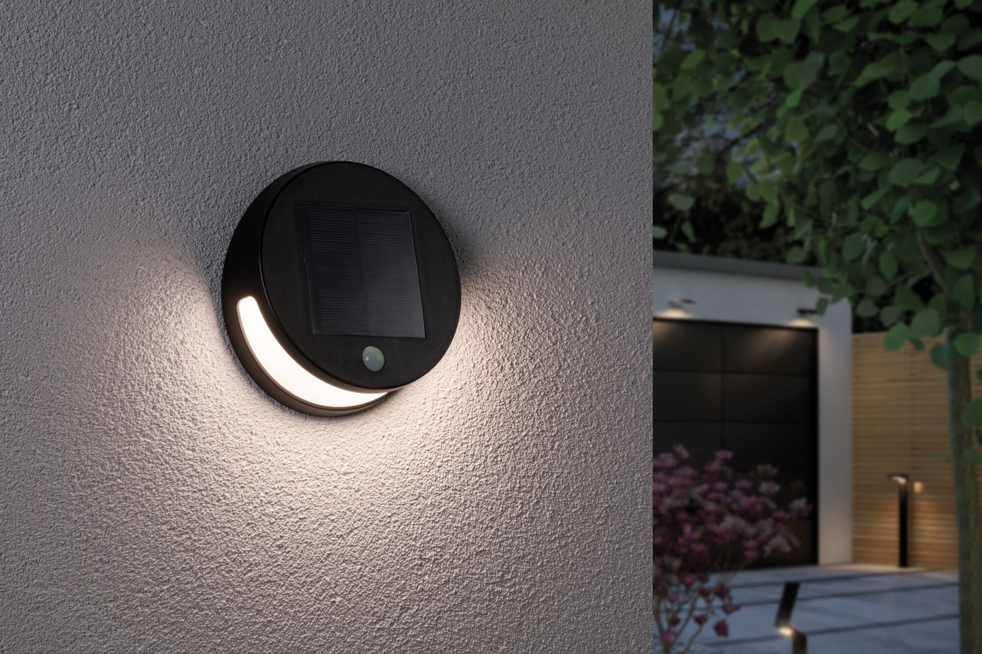 Round black solar wall light with motion sensor on exterior wall, energy-saving LED outdoor lighting