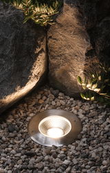 Recessed LED garden light in brushed stainless steel surrounded by pebbles for outdoor lighting