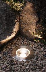 Recessed LED garden light in brushed stainless steel surrounded by pebbles for outdoor lighting