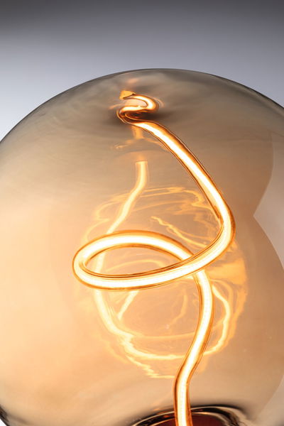 Nahaufnahme einer warmweißen LED-Glühbirne mit spiralförmigem Leuchtfaden aus Glas für dekorative Beleuchtung