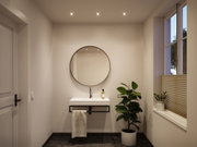 Modernes Badezimmer mit rundem Spiegel, weißem Waschbecken und schwarzem Metallgestell, Pflanze und Fenster