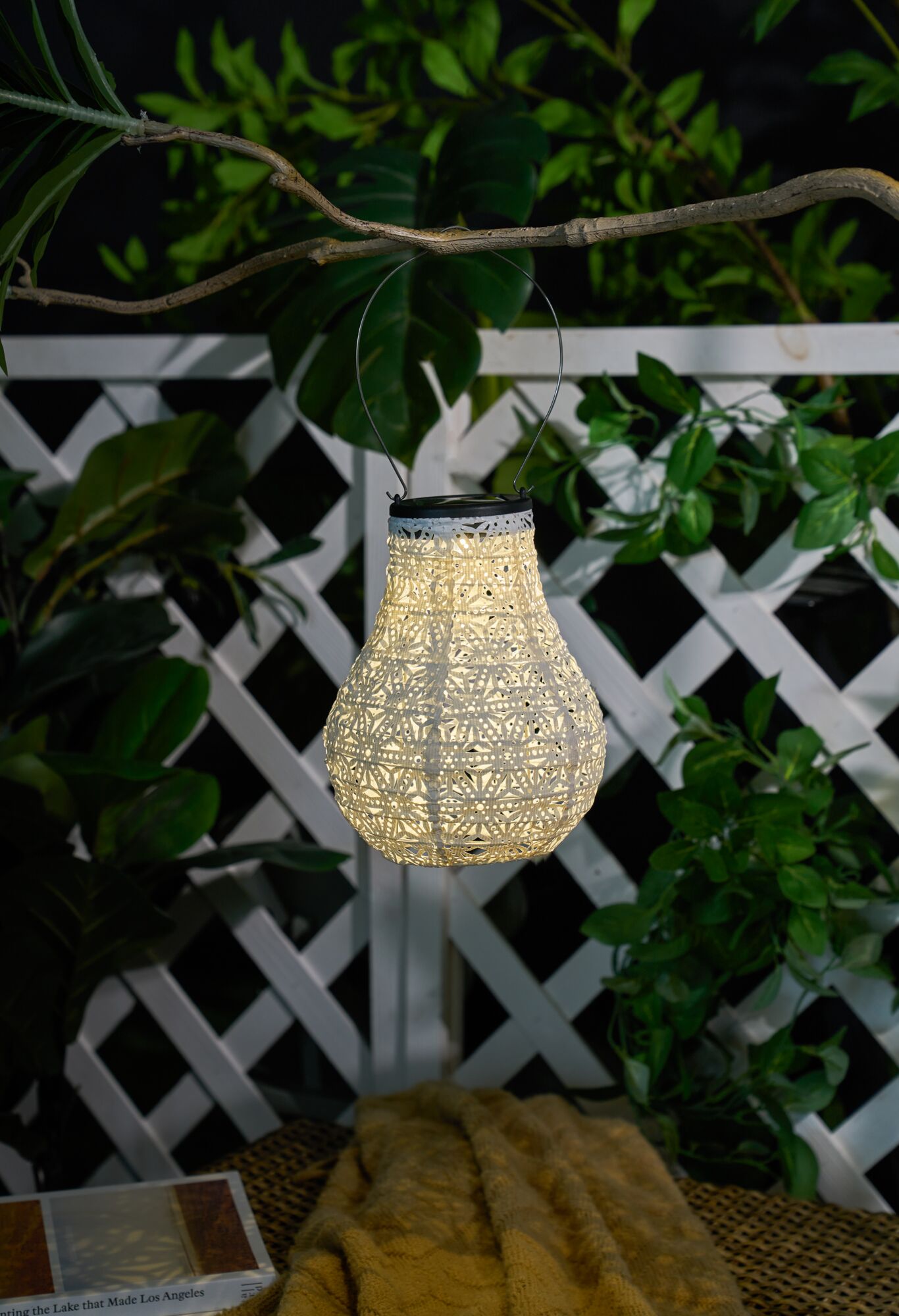 Witte decoratieve metalen solar-lantaarn met patroon hangend buiten, sfeerverlichting tuin.