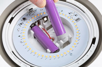 Nahaufnahme von zwei violetten Lithium-Ionen-Akkus in weißem LED-Leuchtengehäuse mit gelben LEDs
