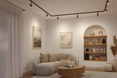 Living room with cream fabric sofa, wooden coffee table and black ceiling spotlights for modern lighting design