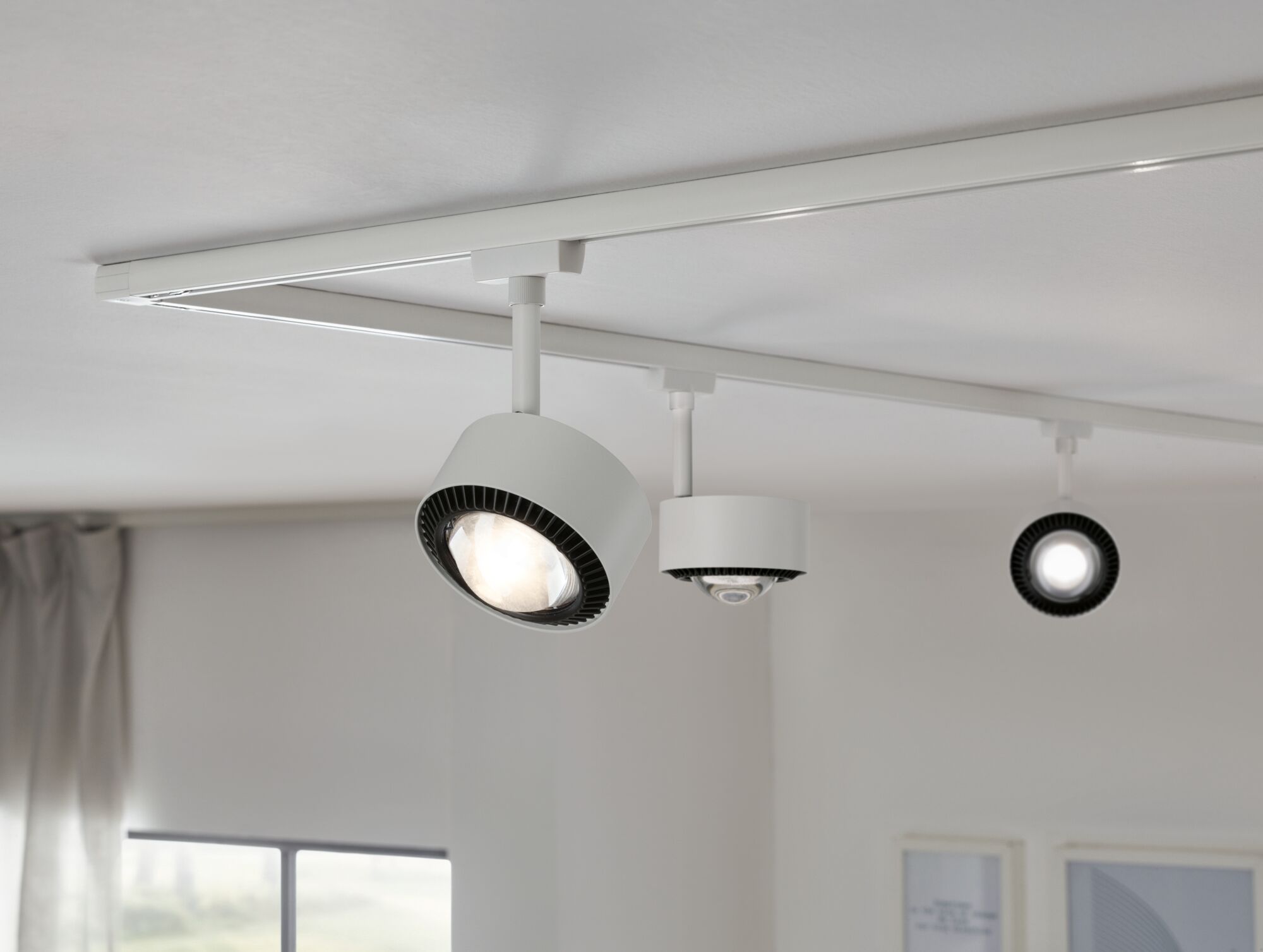 Witte LED-railspots met zwarte koellichaam aan wit plafond voor moderne verlichting