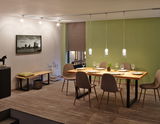 Dining room with wooden table, brown chairs, and modern glass pendant lights on URail track lighting system.