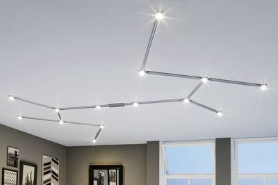 Modular silver LED track lighting on white ceiling with warm white light for modern room illumination