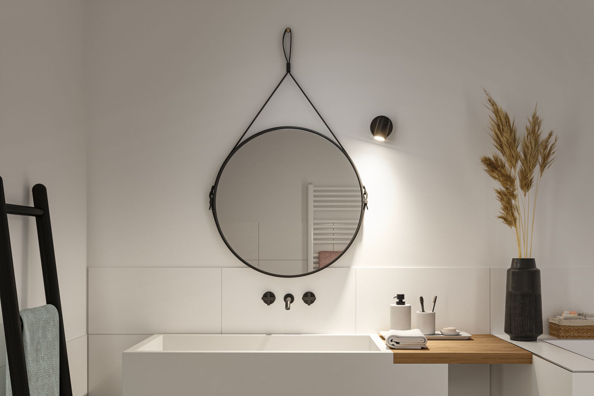 Round black wall mirror with leather strap and black LED wall light above white bathroom sink