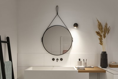 Miroir mural rond noir avec sangle en cuir et applique LED noire au-dessus d'un lavabo blanc