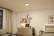 Modernes Wohnzimmer mit quadratischer Deckenleuchte in Weiß, Holzschreibtisch und grünen Pflanzen