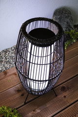 Modern black metal wire lantern with white light on wooden terrace for outdoor lighting