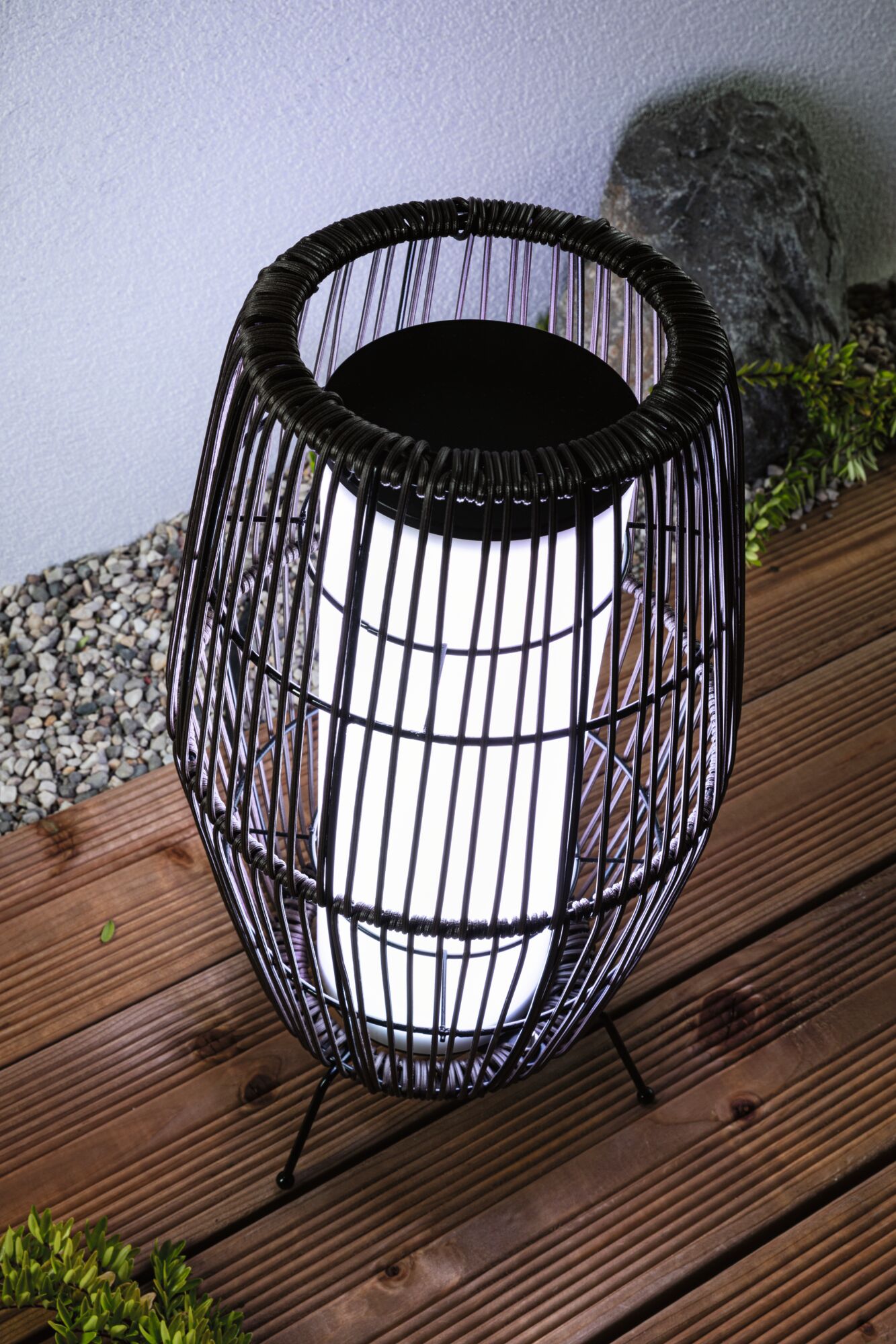 Moderne zwarte metalen draadlantaarn met wit licht op houten terras voor buitenverlichting