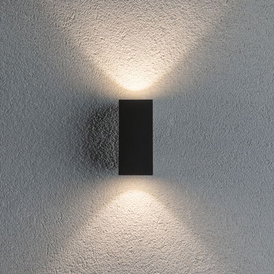 Zwarte aluminium wandlamp met warm wit licht naar boven en beneden op een gestructureerde grijze muur
