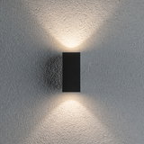 Applique murale noire en aluminium diffusant une lumière blanche chaude vers le haut et le bas sur mur gris texturé