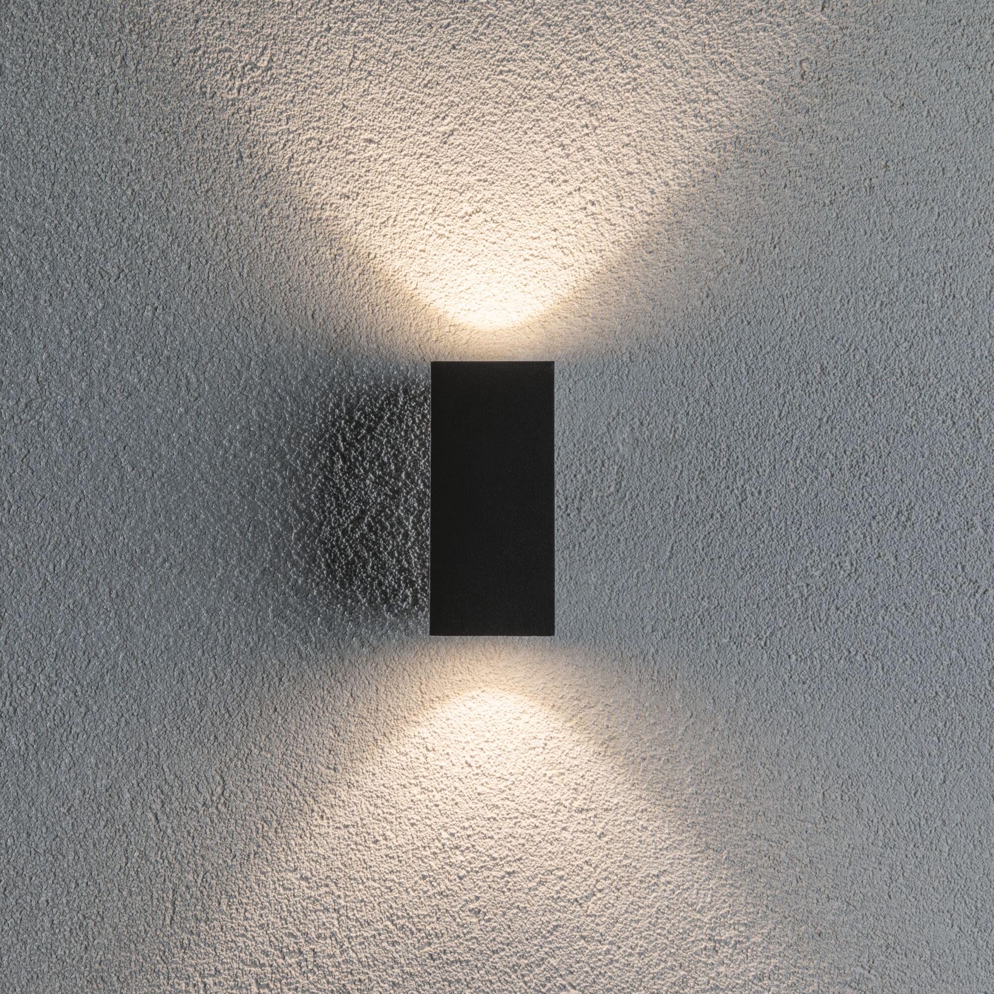 Schwarze LED-Wandleuchte aus Metall mit warmweißem Licht auf strukturierter grauer Wand