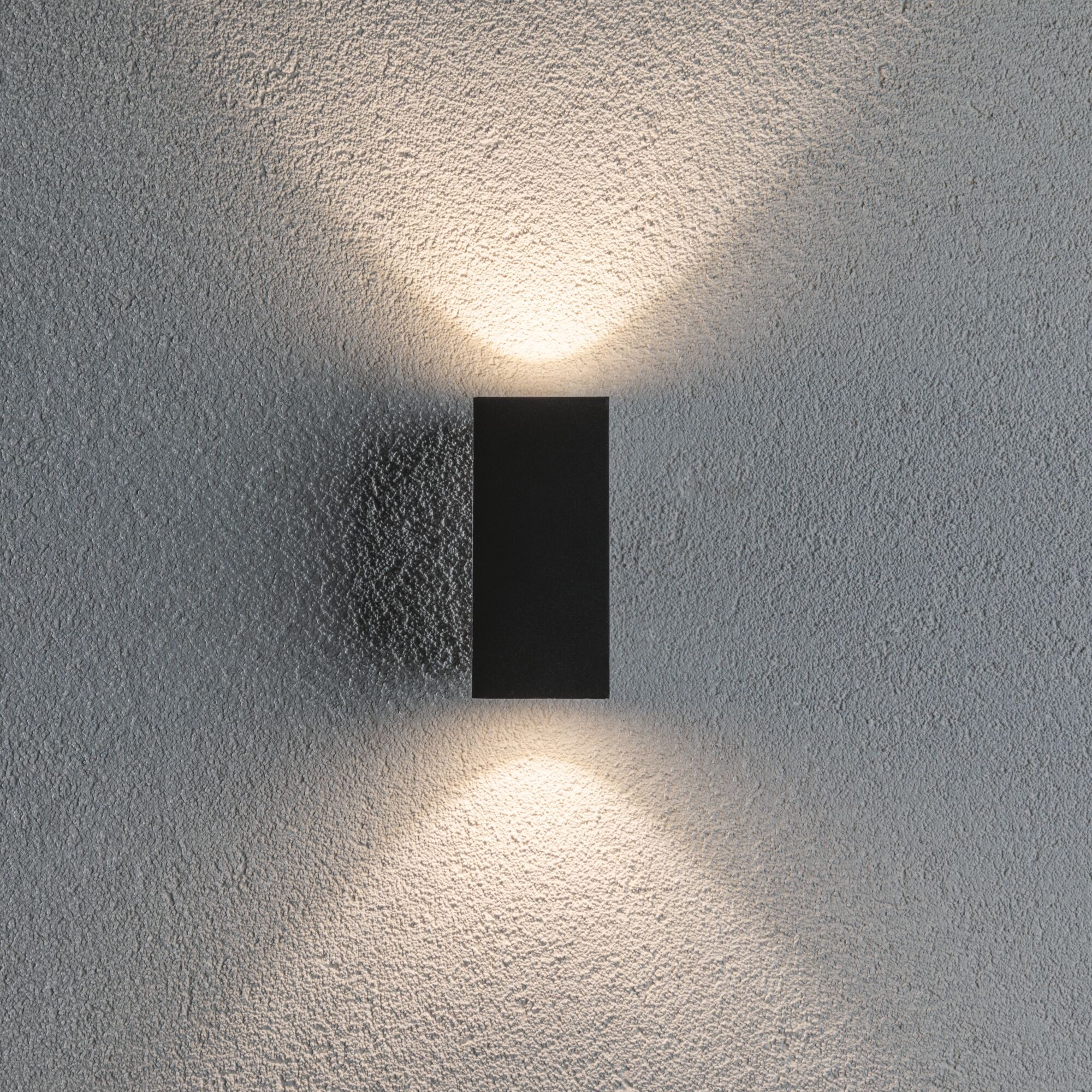 Schwarze LED-Wandleuchte aus Metall mit warmweißem Licht auf strukturierter grauer Wand