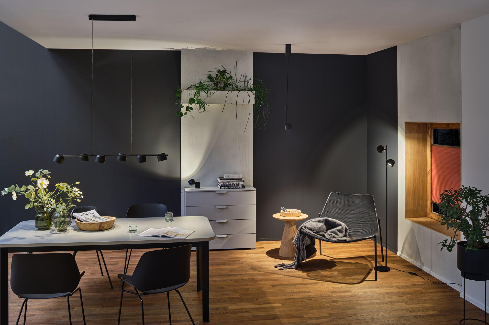 Modern living room with black metal pendant and floor lamps, wooden floor and grey lounge chair