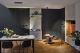 Salon moderne avec suspension et lampadaire noirs en métal, sol en bois et fauteuil gris