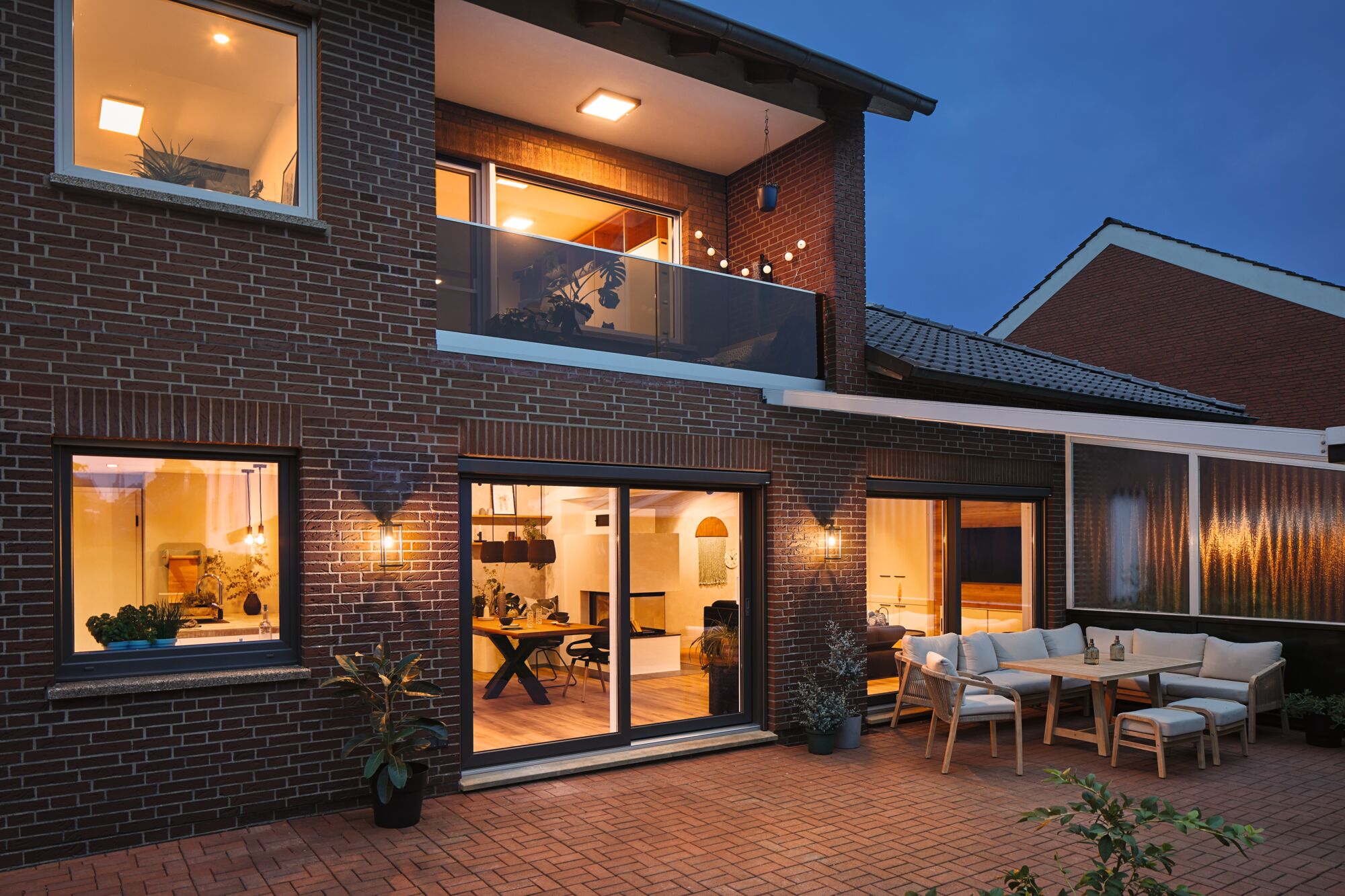 Terrasse éclairée avec éclairage extérieur moderne et ensemble de sièges en bois confortable avec coussins au crépuscule