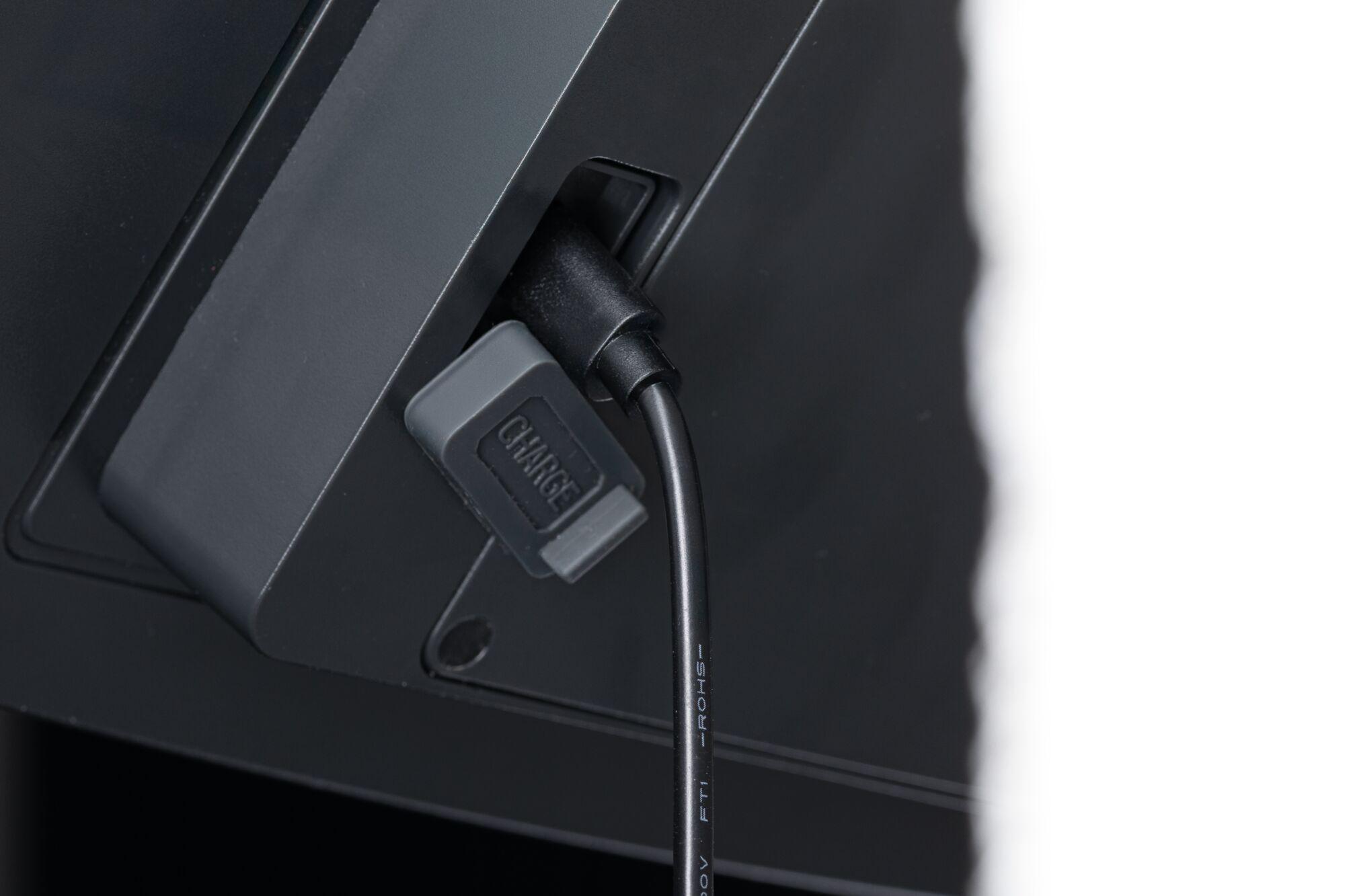 Black charging cable with grey cover connected to a black electronic device for power supply