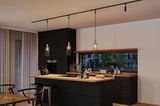 Modern kitchen with black wood island and three black metal pendant lights with warm lighting.