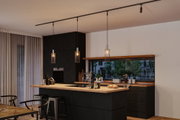 Modern kitchen with black wood island and three black metal pendant lights with warm lighting.