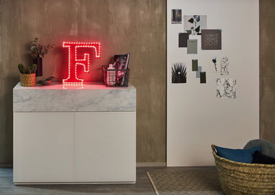 Rotes LED-Licht in Form des Buchstabens F auf weißem Sideboard mit Marmorplatte und Dekoration