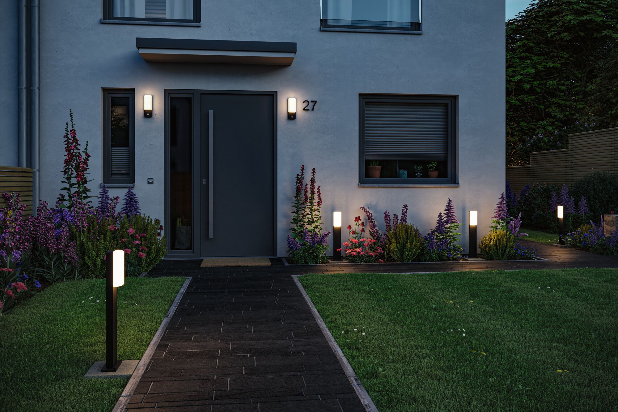 Modern outdoor lighting with black LED post lamps and wall lights on house facade and garden path.