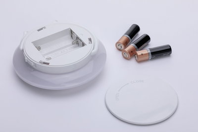 Wit rond batterijvak met deksel en drie AA-batterijen op witte achtergrond, LED-accessoire