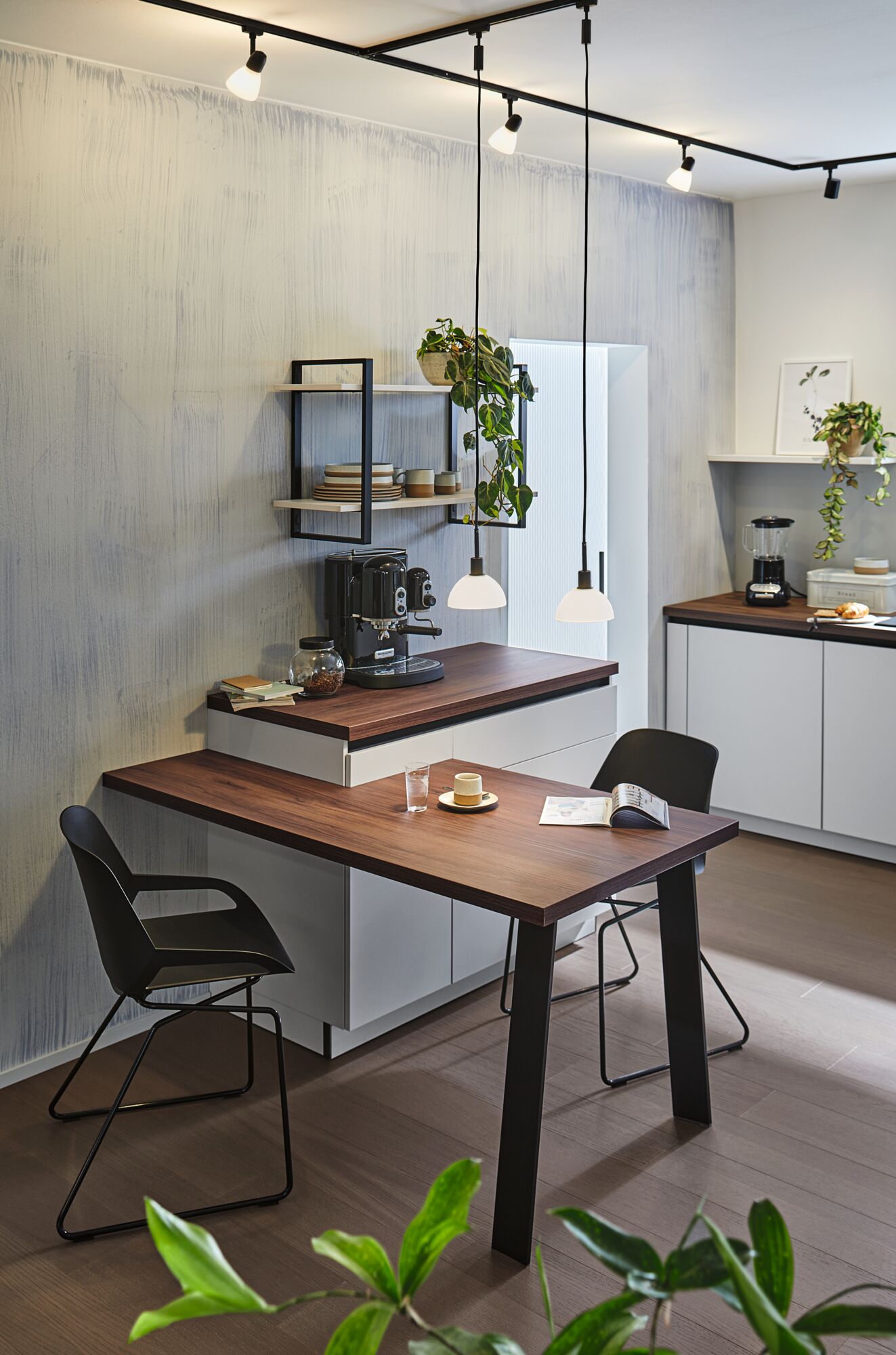 Moderne køkken med træbordplade, sorte stole og minimalistisk pendelbelysning til opholdsrum.