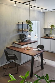 Modern kitchen with wooden countertop, black chairs, and minimalist pendant lighting for living space.