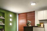 Modern round ceiling light and three square wall lamps in white in a green kitchen with wooden blinds.