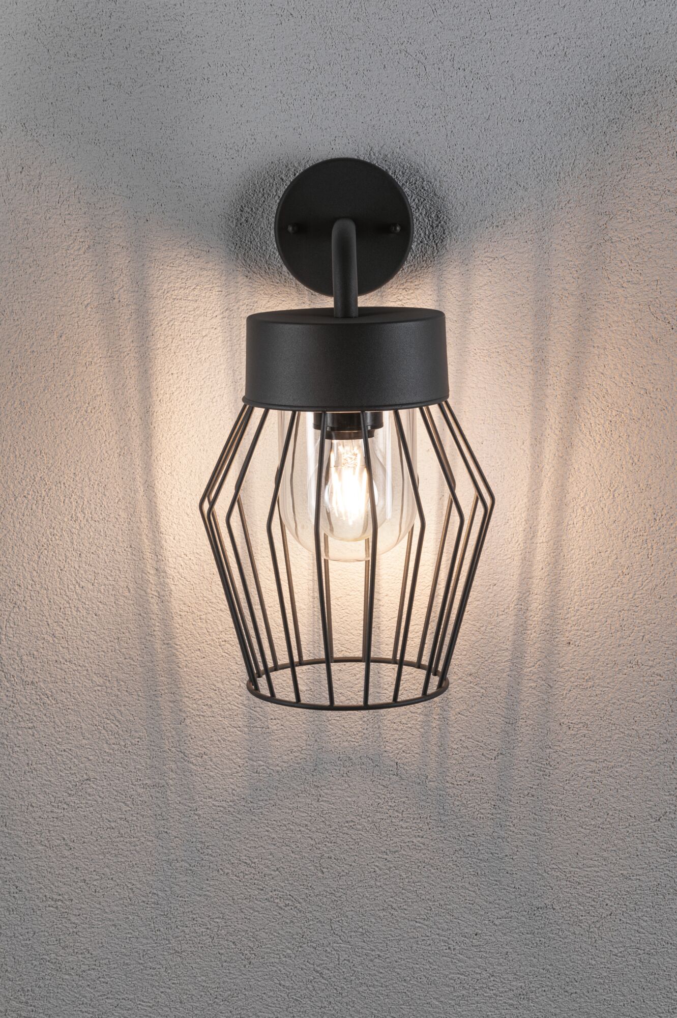 Black metal wall light with cage design and visible bulb for modern indoor lighting