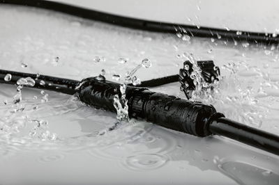 Black waterproof cable connector splashed with water, designed for durable outdoor electrical connections