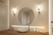 Modernes Badezimmer mit rundem Spiegel, Holzwaschtisch und zwei Wandlampen mit Glaslampenschirmen.