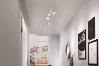 Modern white ceiling spotlight with three LED lights in hallway with mirror and wall art.