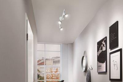 Modern white ceiling spotlight with three LED lights in hallway with mirror and wall art.