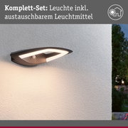 Moderne Außenwandleuchte in Schwarz mit integriertem LED-Licht und Bewegungsmelder an weißer Wand