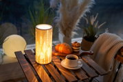 Ceramic table lamp with warm light and leaf pattern on wooden table beside coffee and pastries