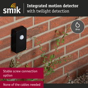 Black motion detector with integrated twilight sensor mounted on red brick wall, IP44 rated outdoor sensor